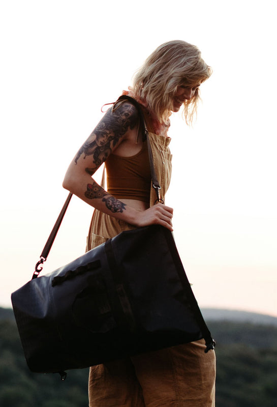woman is shown with a the so ill x on the roam 25L dirt bag and a mountainous background