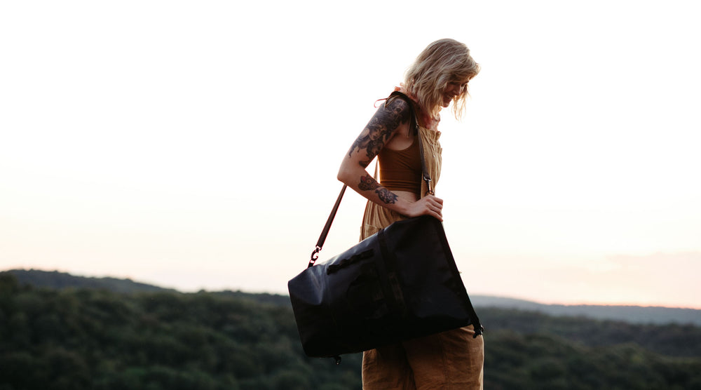 woman is shown with a the so ill x on the roam 25L dirt bag and a mountainous background