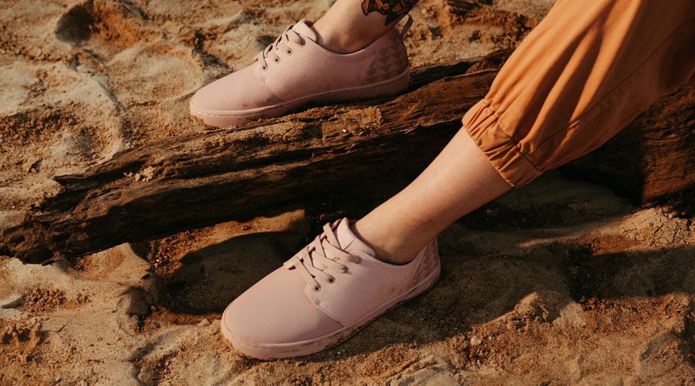 So iLL x On The Roam Jason Momoa Collection Dirt Pink Wino Shoes shown being worn, resting on a log and rocks.