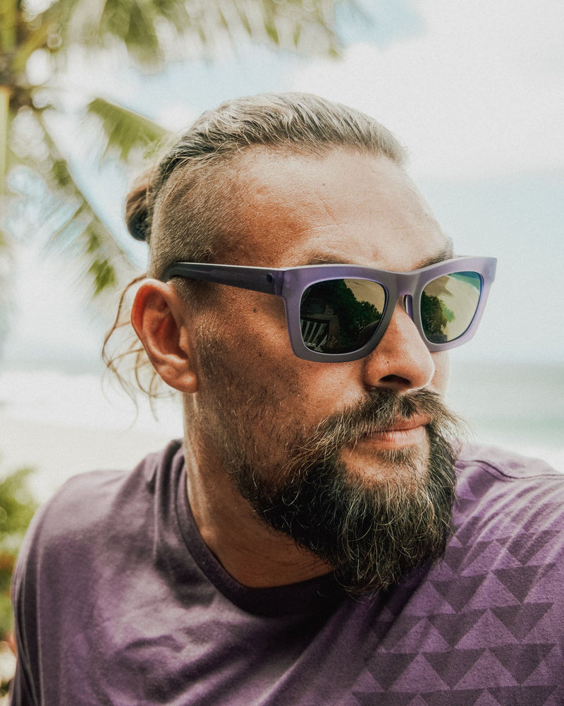 Close-up of Jason Momoa wearing the Unity Purple Nakoa Tee and Unity Purple Crasher sunglasses